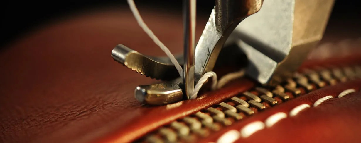 Close-up leather stitching beside a zipper